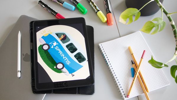 Tablet mit digitaler Illustration, Zeichenstiften, Notizbuch und Pflanze